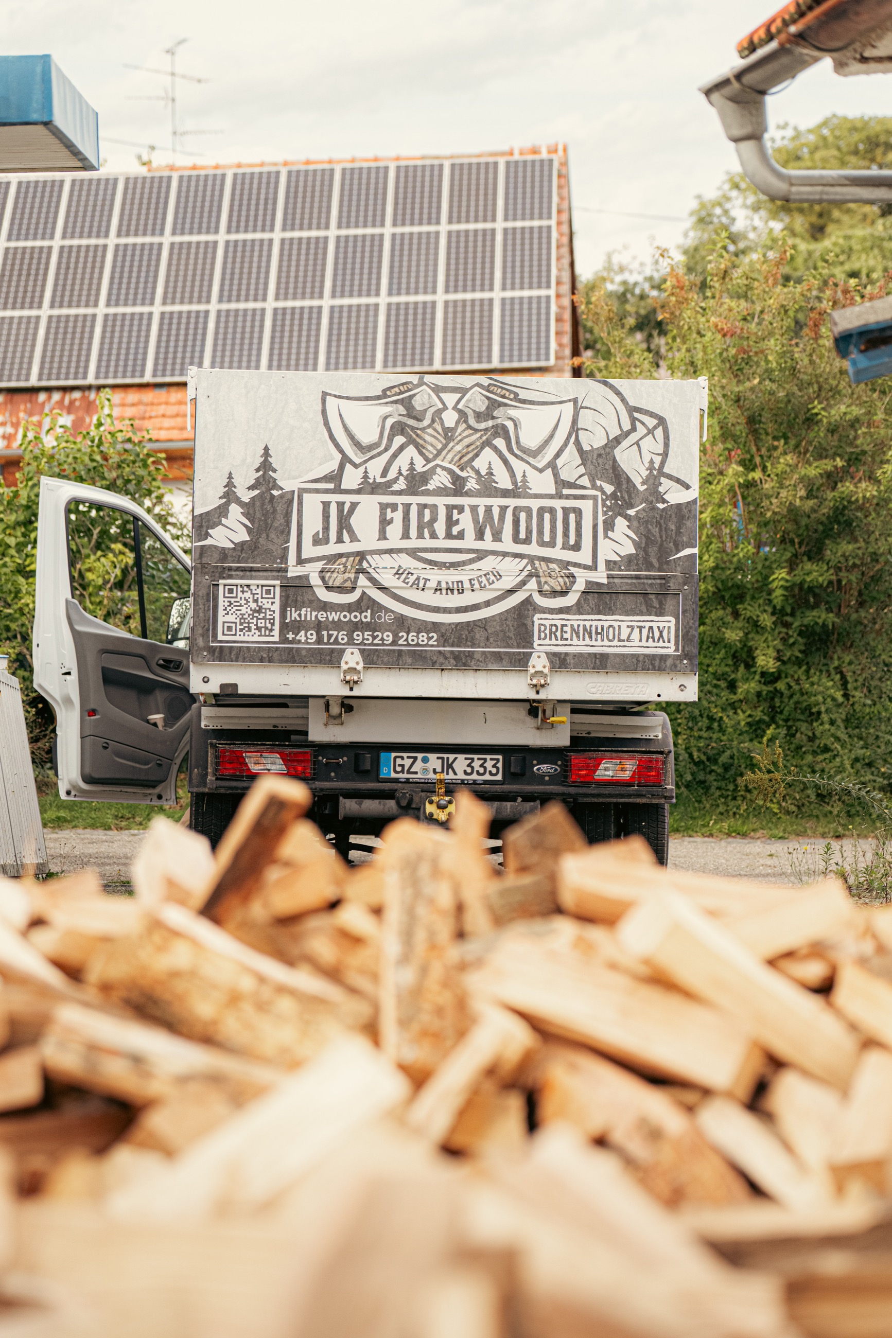 Brennholztaxi von hinten mit Holz davor